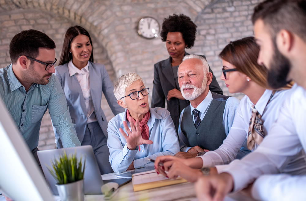 Older worker leading discussion in multi-generational team.